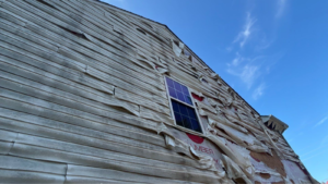 Storm damaged siding Virginia Beach home with cracked and dented exterior panels